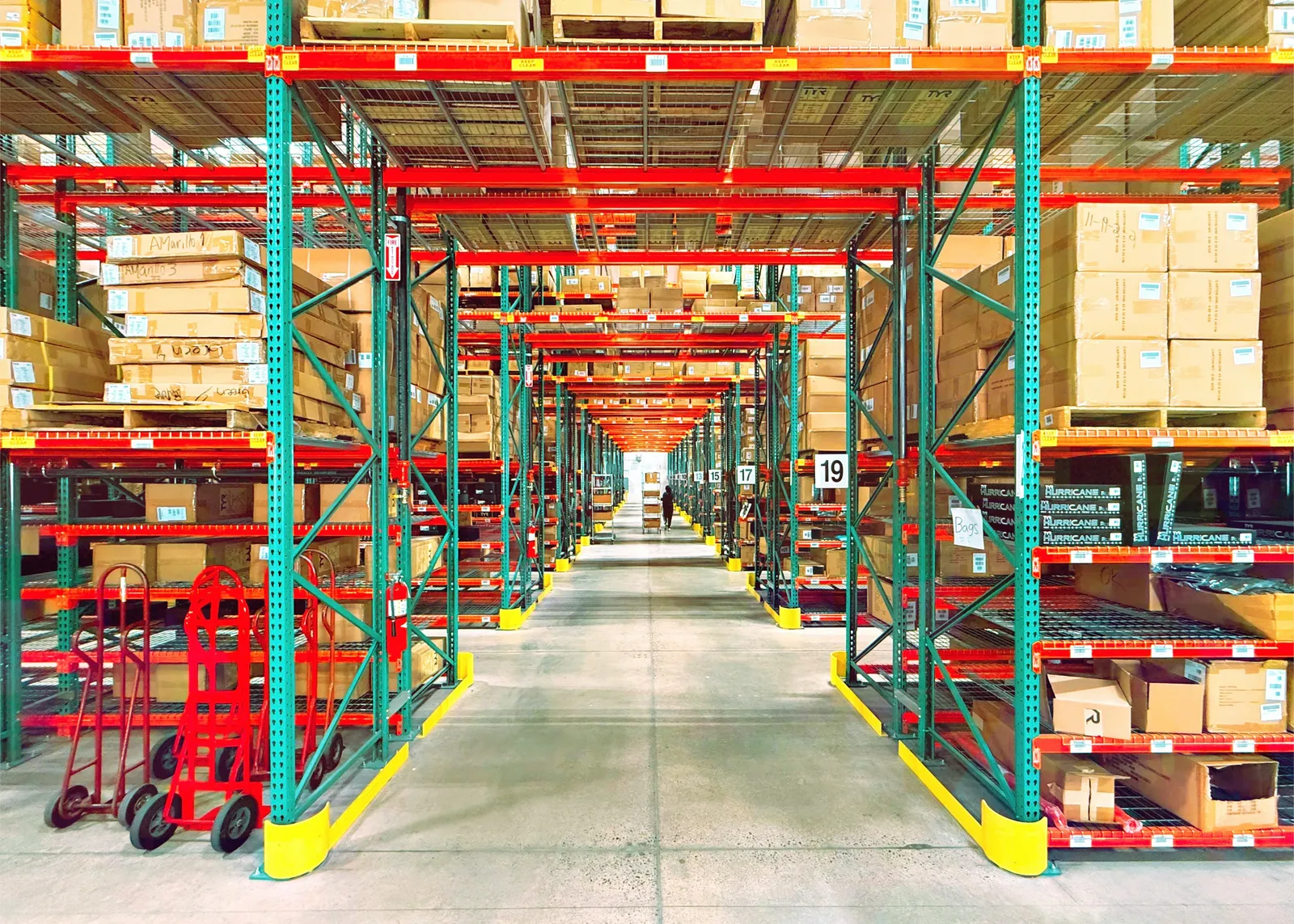 Long warehouse aisle lined with pallet racks and boxed inventory.