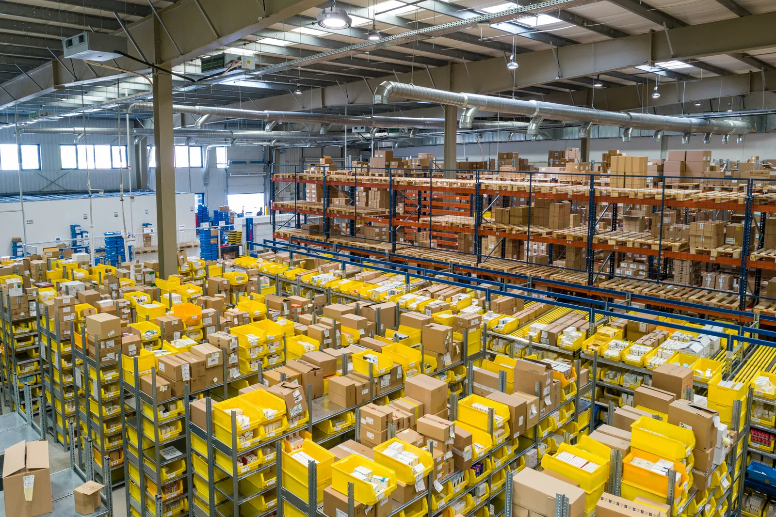 Warehouse storage racks filled with parcels and yellow order-picking bins.
